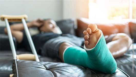 Ein Mann liegt im Krankenbett, sein Bein steckt in einem Gipsverband