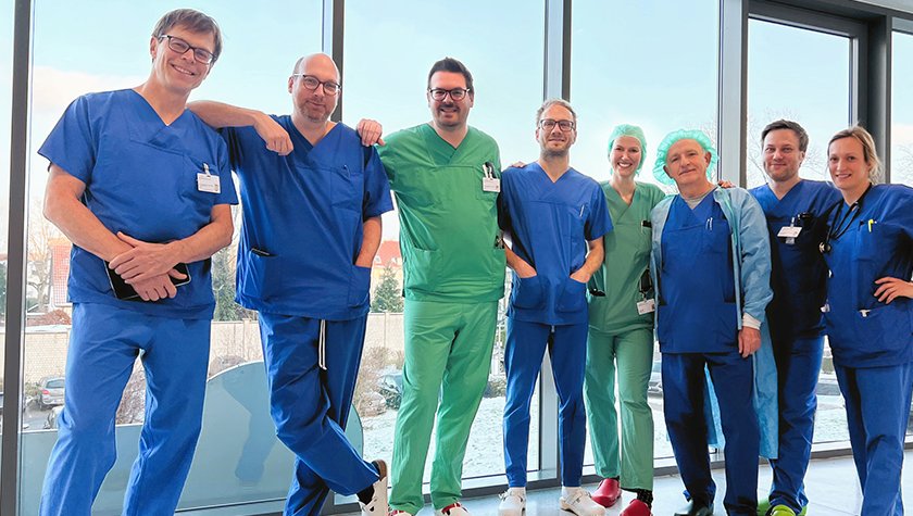 Anästhesie-Team bestehend aus 8 Personen steht vor einer Glaswand
